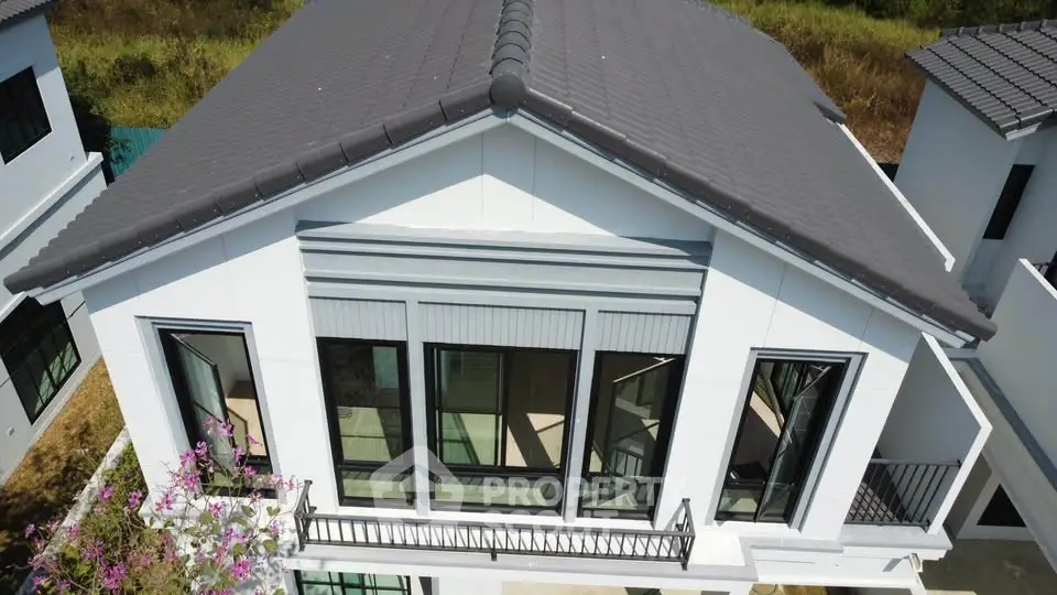 Modern two-story house with large windows and balcony, ideal for family living.