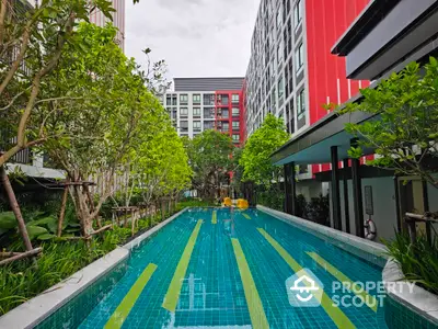 Modern apartment complex with a stunning outdoor pool surrounded by lush greenery.