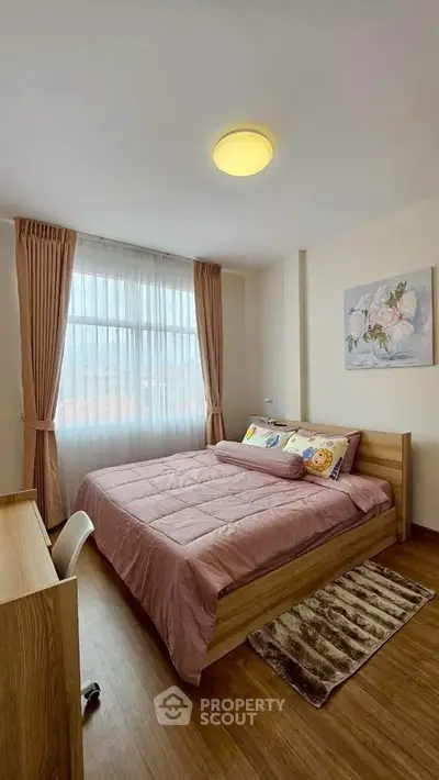 Cozy bedroom with wooden flooring, large window, and stylish decor in modern apartment.