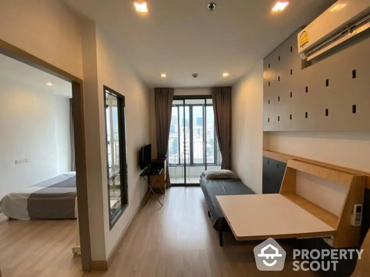 Modern studio apartment with city view, featuring compact living space and bedroom area.