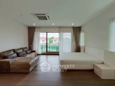 Spacious modern bedroom with large windows and cozy seating area, offering a serene and inviting atmosphere.