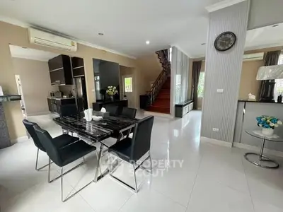 Spacious modern dining area with sleek black table and chairs, open layout, and elegant staircase.