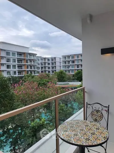 Charming balcony view overlooking lush gardens and modern apartment buildings.