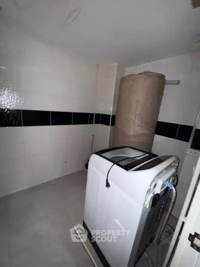 Compact laundry room with washing machine and water heater, ideal for efficient home living.