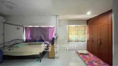 Spacious bedroom with simple decor and ample natural light, featuring a large bed and built-in wardrobe.
