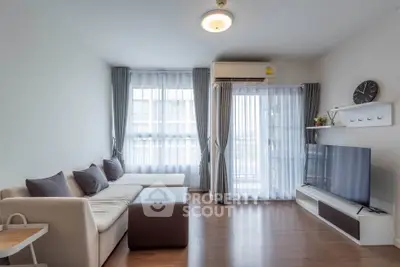 Modern living room with large windows, cozy sofa, and flat-screen TV, perfect for relaxation.