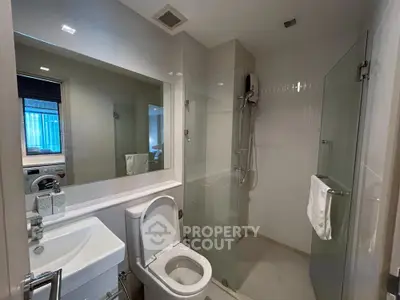 Modern bathroom with glass shower and sleek fixtures in contemporary apartment.