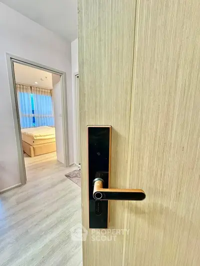 Modern bedroom entrance with sleek door handle and cozy interior view.