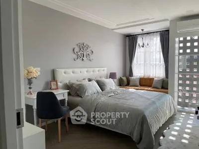 Elegant bedroom with plush bed, cozy seating area, and stylish decor in modern apartment.
