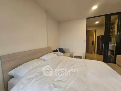 Modern bedroom with cozy bed and open view to kitchen area