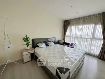 Spacious bedroom with large window and modern decor in a high-rise apartment.