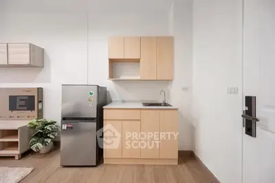Modern kitchen with sleek cabinets and stainless steel fridge in a minimalist apartment.