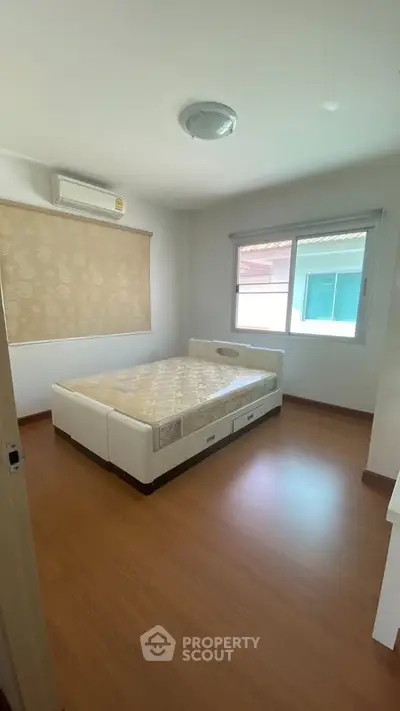 Spacious bedroom with large window and modern bed in a bright, airy apartment.