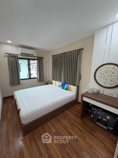 Cozy bedroom with wooden flooring and large window for natural light
