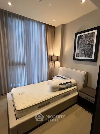 Modern bedroom with stylish decor and natural light, featuring a comfortable bed and elegant furnishings.