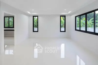 Spacious empty room with large windows and glossy white flooring, offering a bright and airy atmosphere.