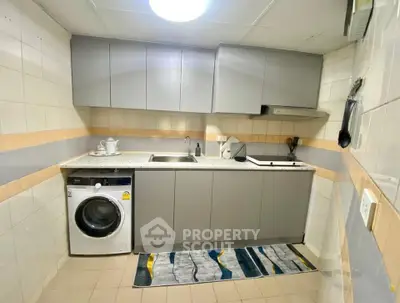 Modern kitchen with sleek cabinets and built-in washing machine in stylish apartment.
