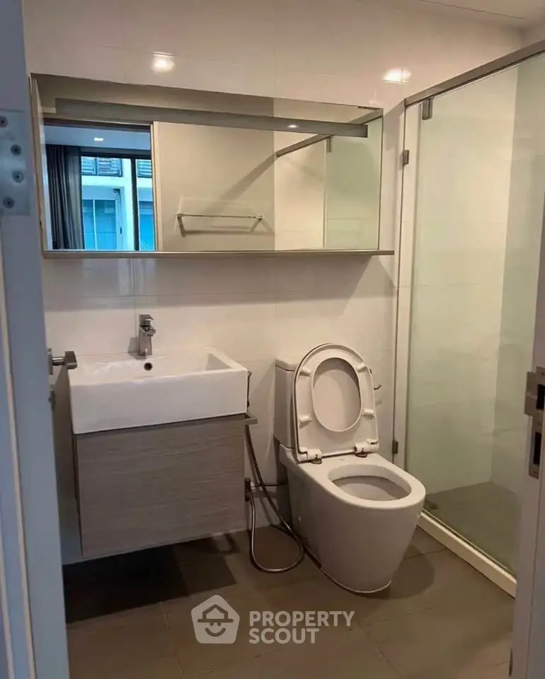 Modern bathroom with sleek fixtures and glass shower enclosure in a contemporary apartment.