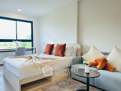 Modern bedroom with cozy decor and large window offering natural light.