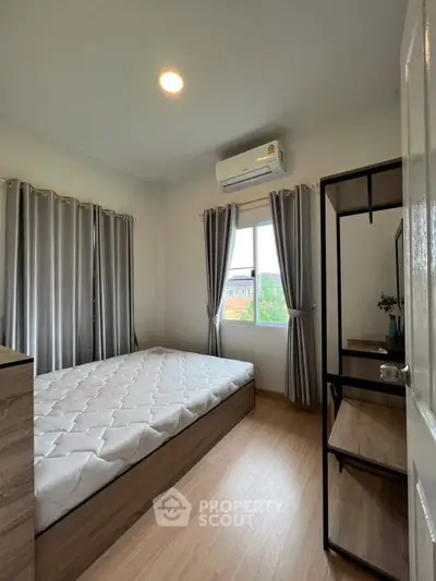 Cozy bedroom with natural light, featuring a comfortable bed and modern decor, perfect for relaxation.