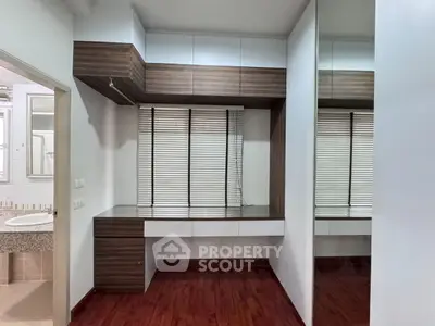 Modern study area with sleek wooden desk and large mirror, adjacent to a bathroom.