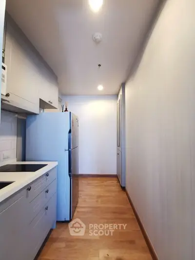 Modern kitchen with sleek cabinetry and stainless steel fridge in a compact layout.