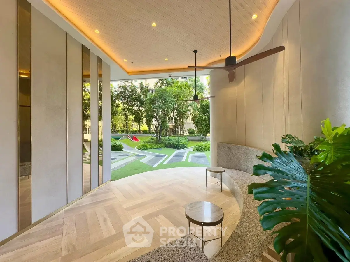 Modern building entrance with stylish seating and lush garden view