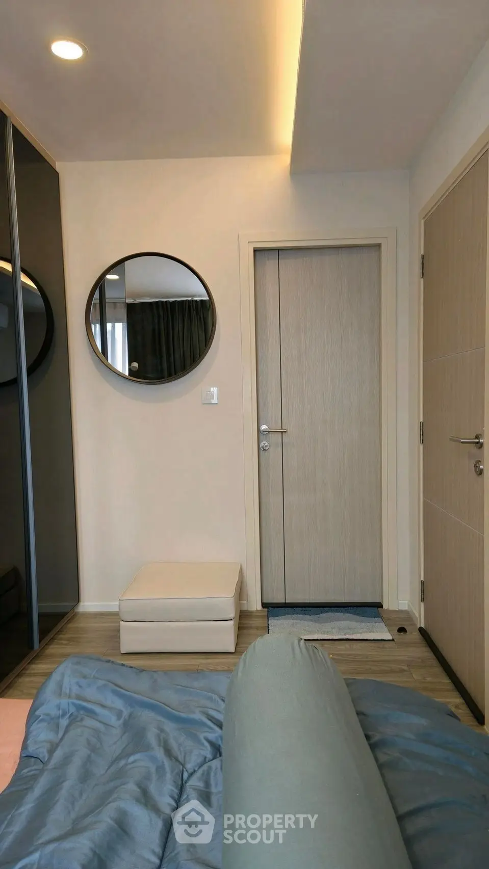 Modern bedroom with stylish decor and round mirror, showcasing a cozy and inviting atmosphere.