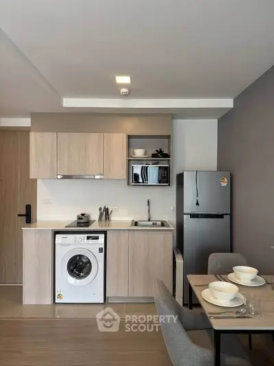 Modern kitchen with sleek appliances, washing machine, and dining area in a stylish apartment.