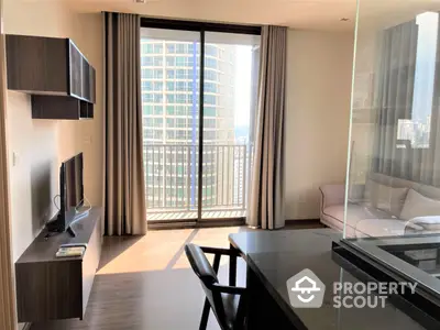 Sunlit modern living room with floor-to-ceiling windows leading to a spacious balcony, featuring sleek furniture and wooden flooring.