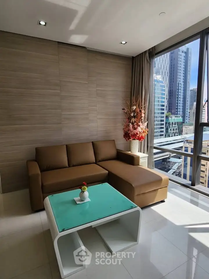 Modern living room with city view, featuring a brown sofa and stylish decor in a high-rise apartment.