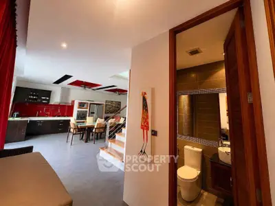 Modern open-layout kitchen and dining area with adjacent bathroom in stylish apartment.