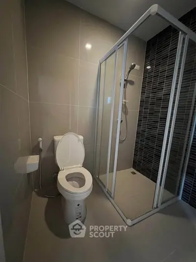 Modern bathroom with sleek shower enclosure and toilet in a minimalist design.