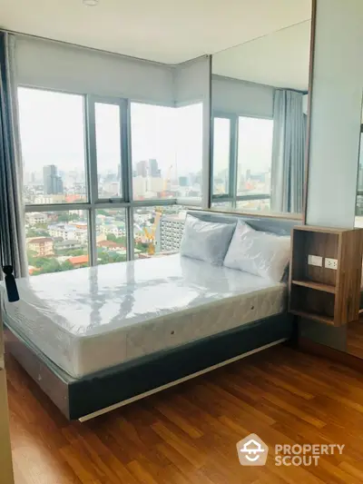 Modern bedroom with city view and large windows in high-rise apartment