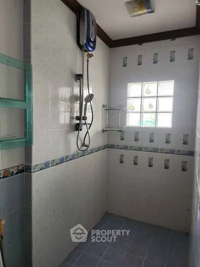 Compact bathroom with tiled walls and electric shower heater