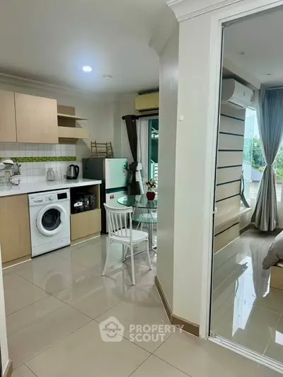 Modern apartment with open kitchen and cozy dining area, featuring a washing machine and stylish decor.