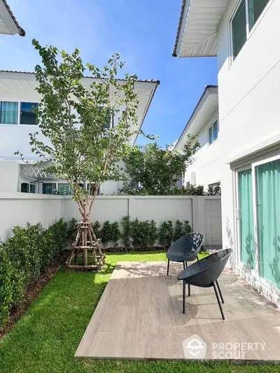 Charming backyard with modern patio chairs and lush greenery in a serene residential setting.