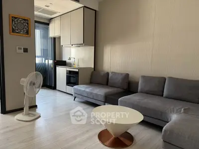 Modern living room with sleek kitchen and stylish furniture in open layout.