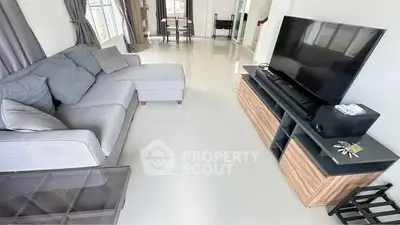 Spacious living room with modern furniture and large TV, ideal for relaxation.