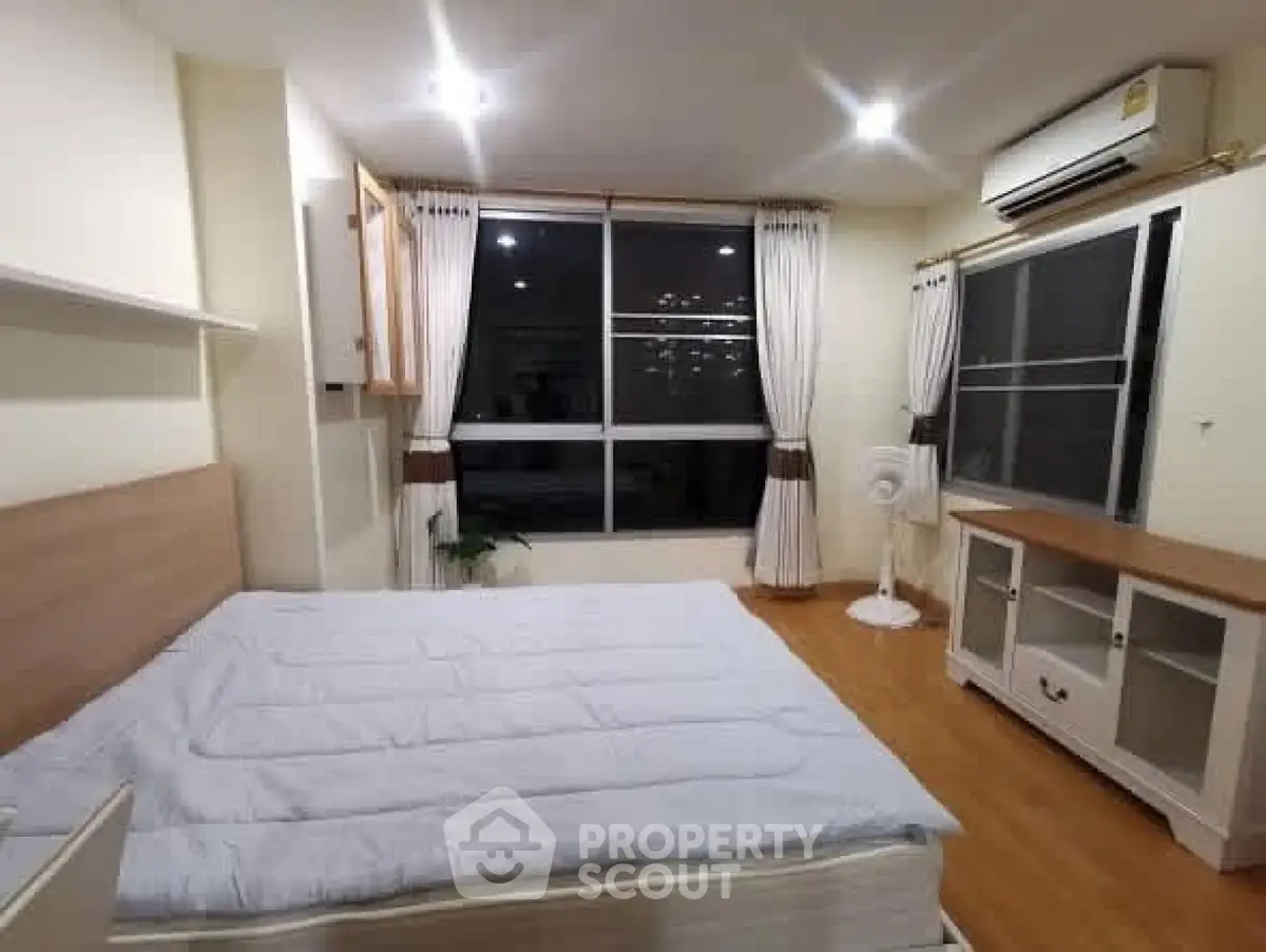 Spacious bedroom with large window and modern furnishings in a cozy apartment.