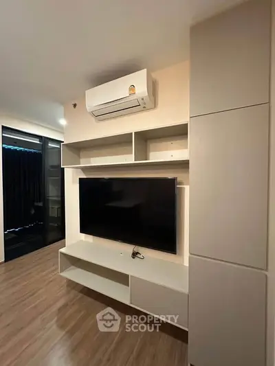 Modern living room with sleek TV unit and air conditioning, featuring stylish wooden flooring.