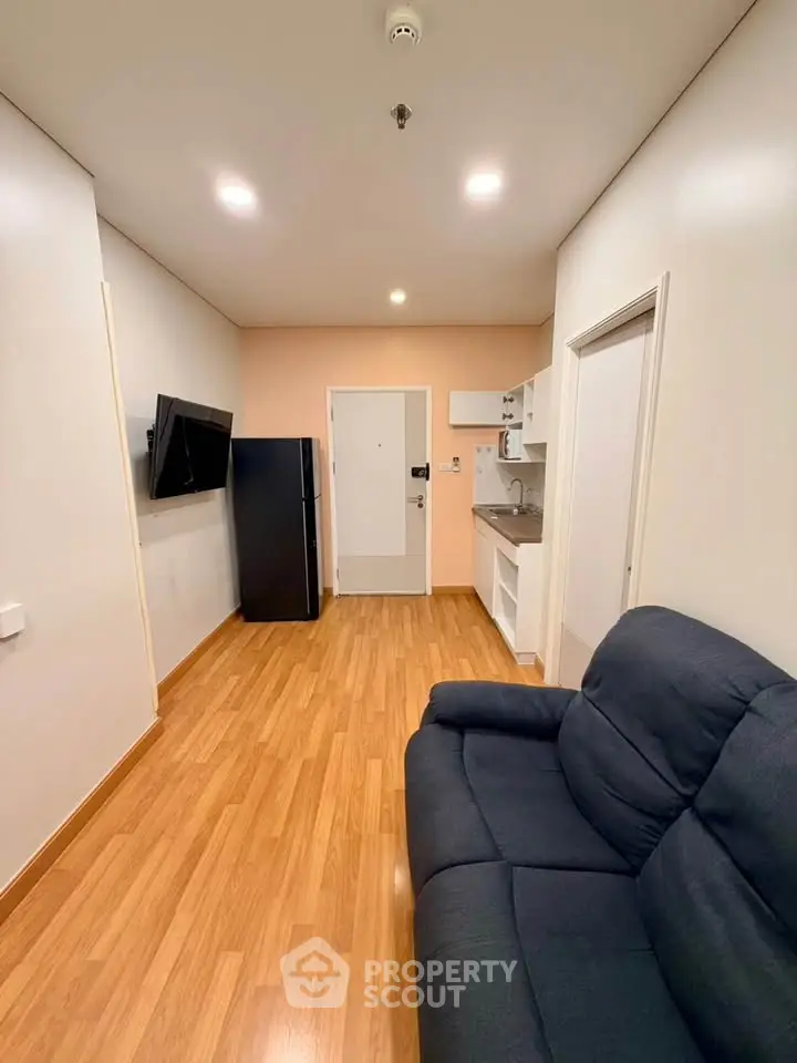 Modern studio apartment with sleek wooden flooring and compact kitchen area.