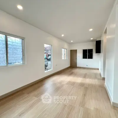 Spacious and bright living room with wooden flooring and large windows in modern home.