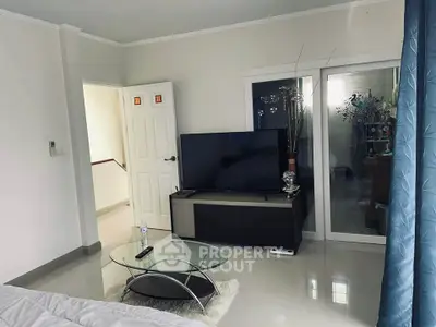 Modern living room with sleek TV stand and glass coffee table, featuring elegant decor and natural light.