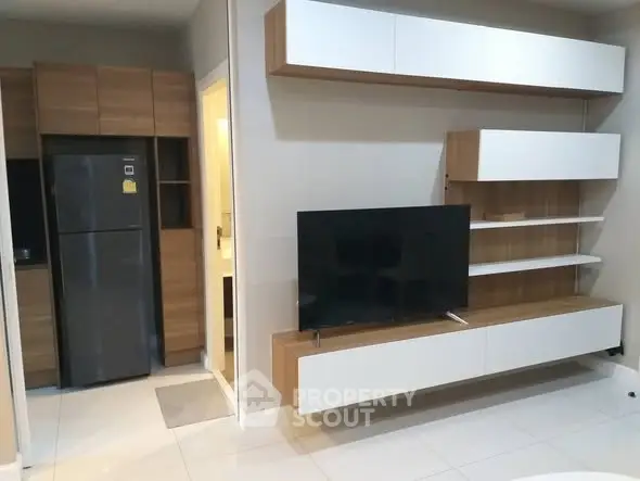 Modern living room with sleek TV unit and integrated kitchen appliances.
