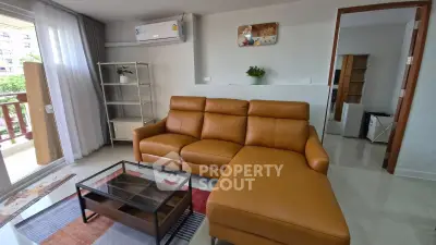Modern living room with brown leather sofa and glass coffee table, featuring a balcony view.