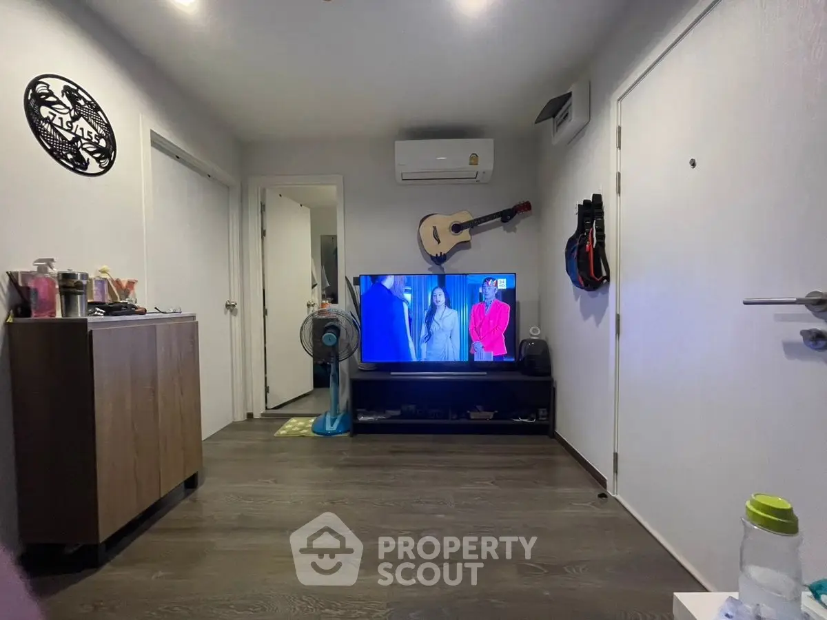 Modern living room with wall-mounted guitar and air conditioning, featuring a sleek TV setup.