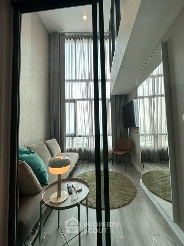 Modern living room with high ceilings and large windows, featuring stylish furniture and elegant decor.