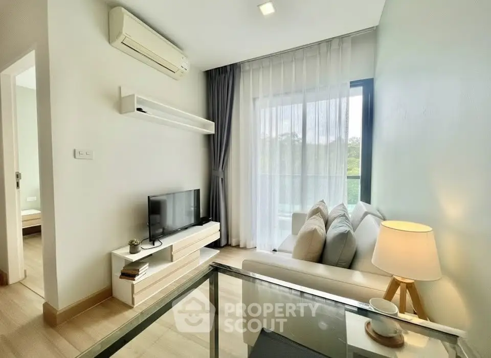 Modern living room with natural light, cozy sofa, and sleek TV setup in a stylish apartment.