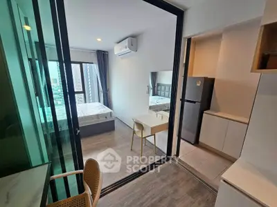 Modern studio apartment with glass partition, featuring a cozy bedroom and compact kitchen area.